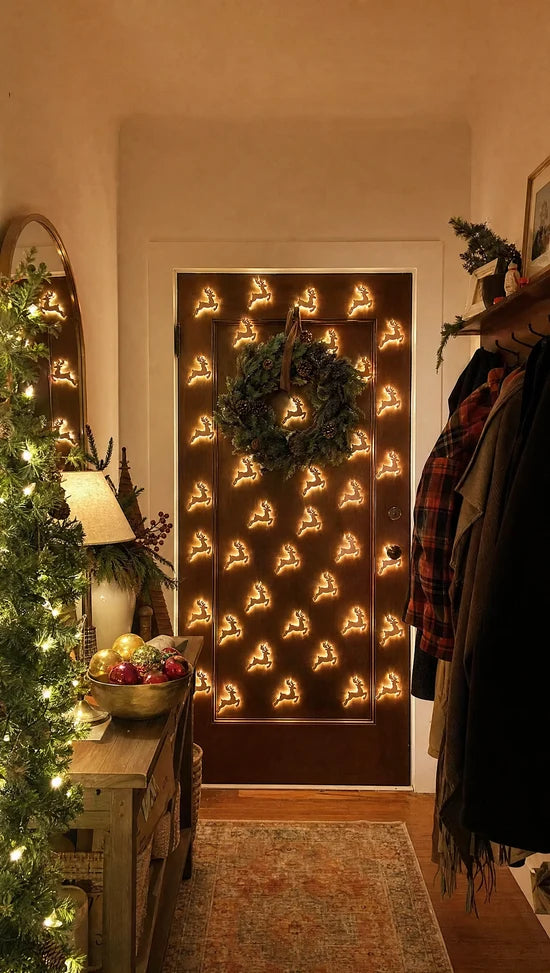 Lit ReinGlow reindeer lights stuck on a front door with a wreath